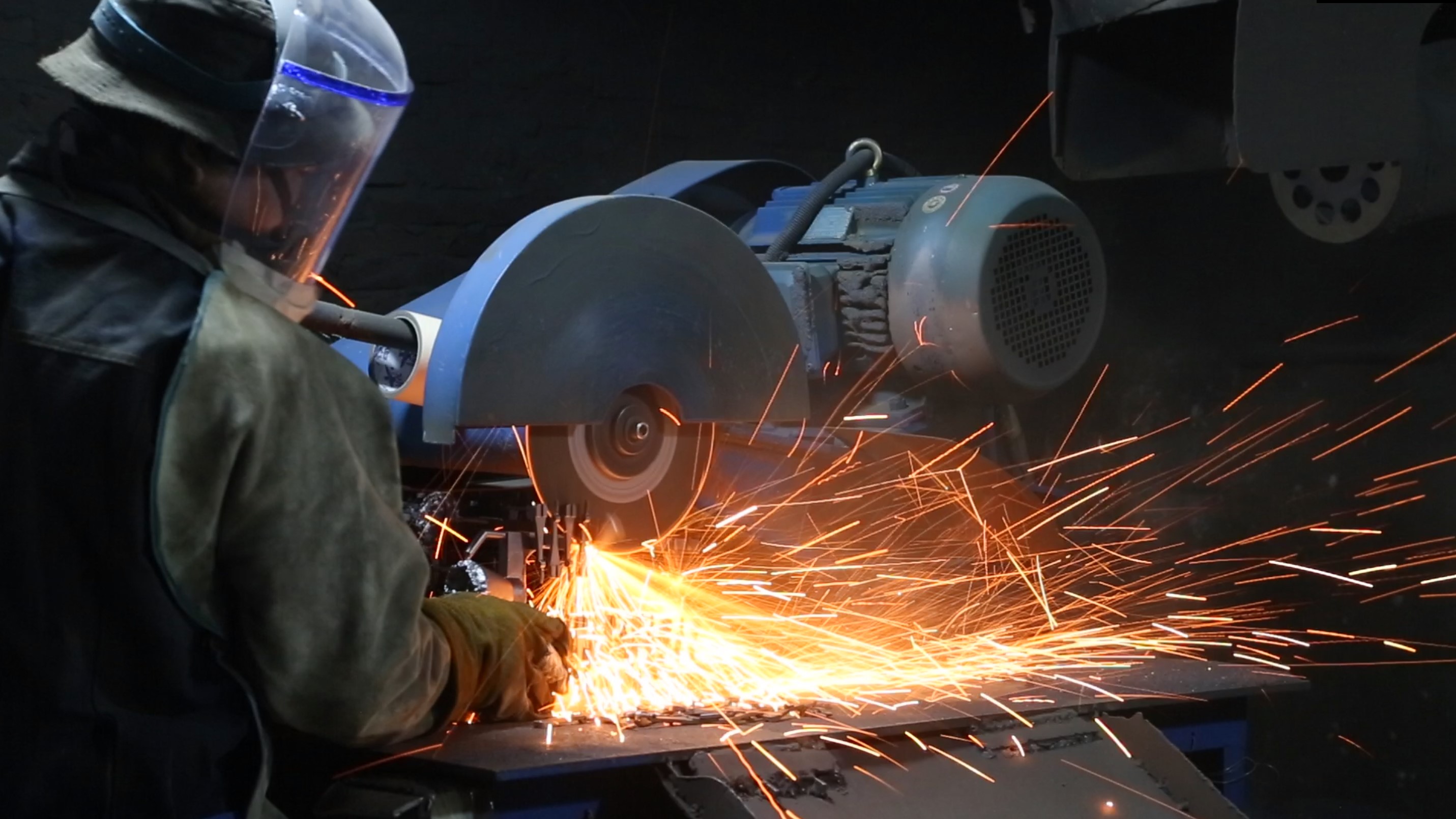 Worker grinding and cleaning a steel casting after the investment casting process